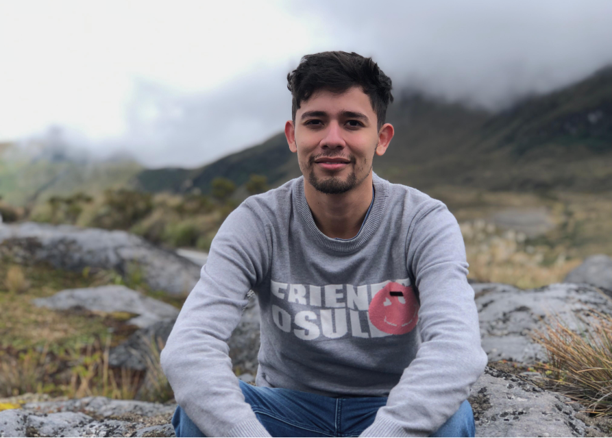 Antonio Sterling sentado en rocas con paisaje del Nevado del Ruiz, Colombia.